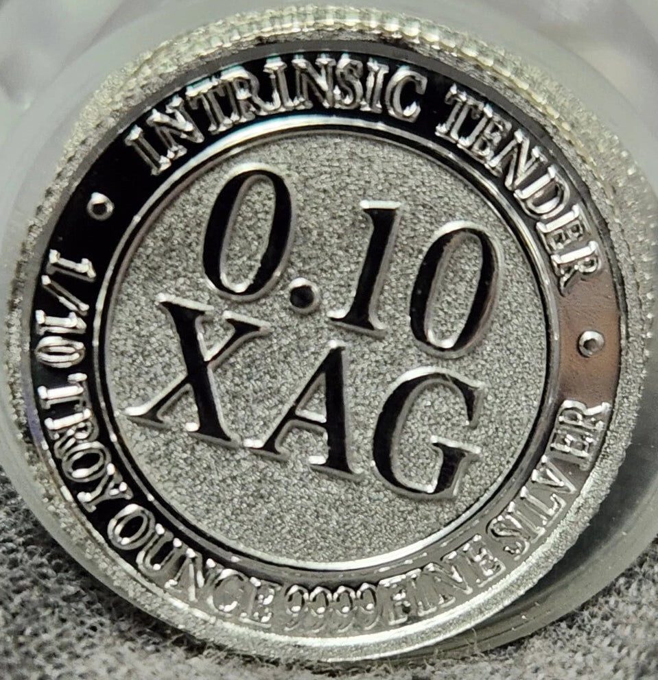 Silver bullion round coin with '0.10 XAG' text on a textured surface